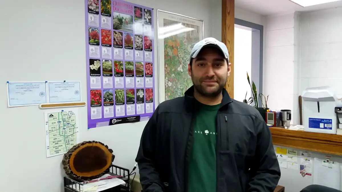 An ArborCare arborist in the office in front of tree and shrub identification charts